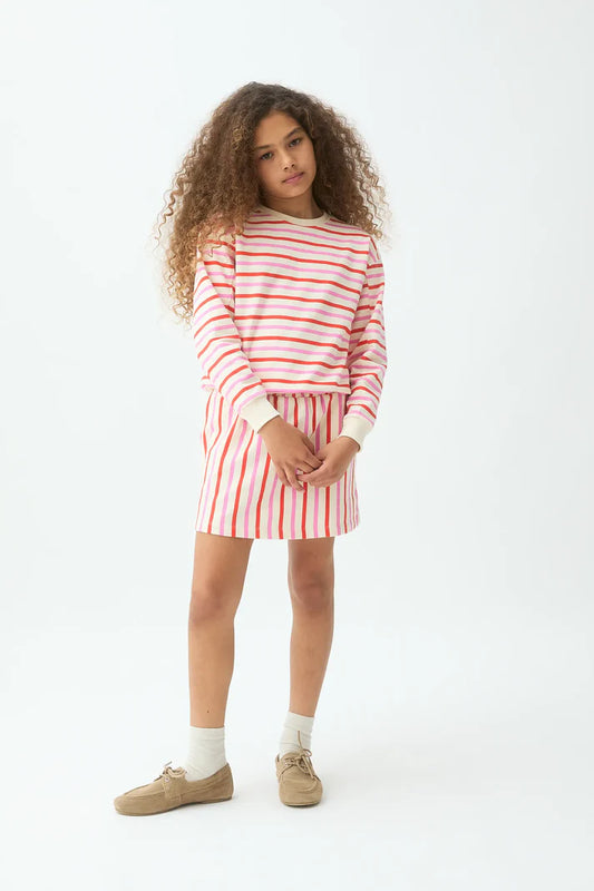 Meisje draagt gestreepte sweater in oranje en ecru van Compañia Fantástica