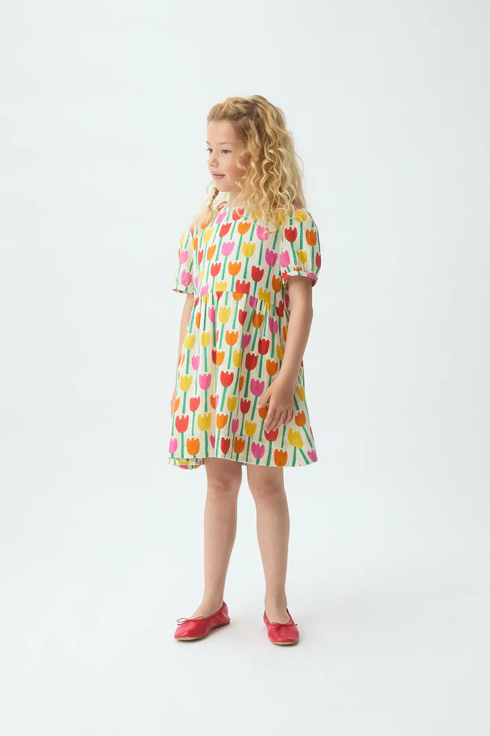 Meisje draagt ecru jurk met all-over print van kleurrijke tulpen van Compañia Fantástica