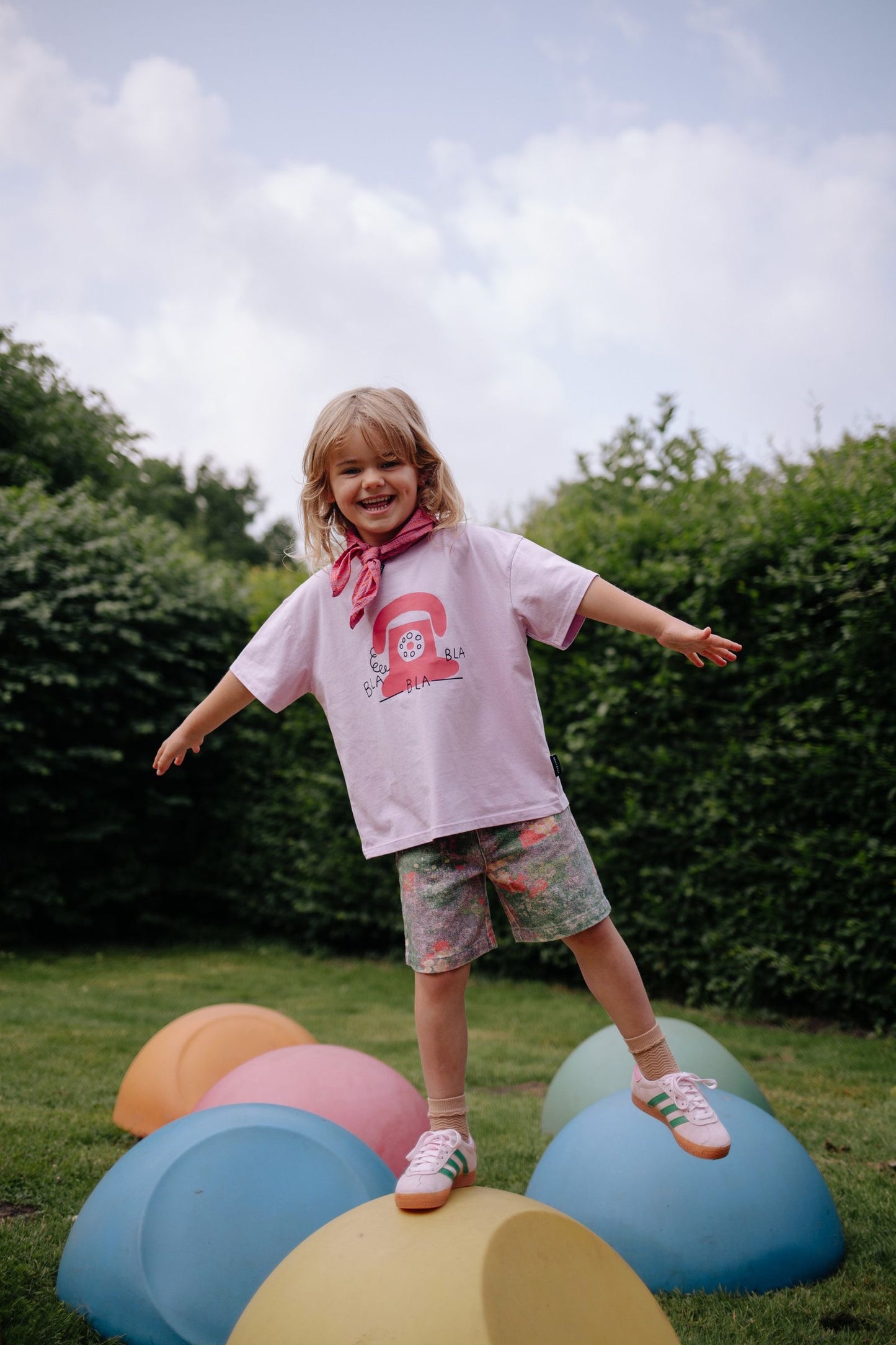 Meisje draagt lichtroze t-shirt met telefoonprint op gekleurde short
