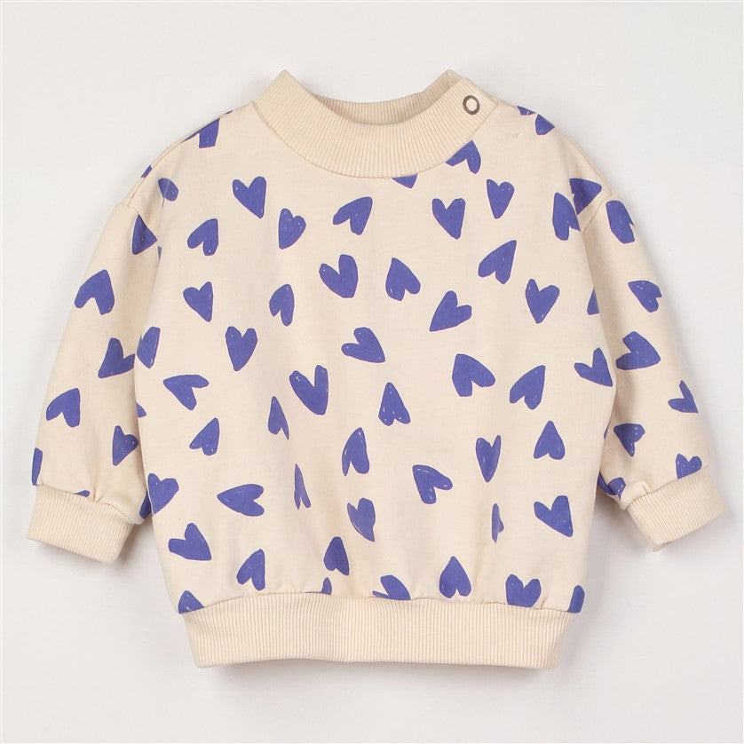 Crèmekleurige baby sweater met all-over blauwe hartjes.