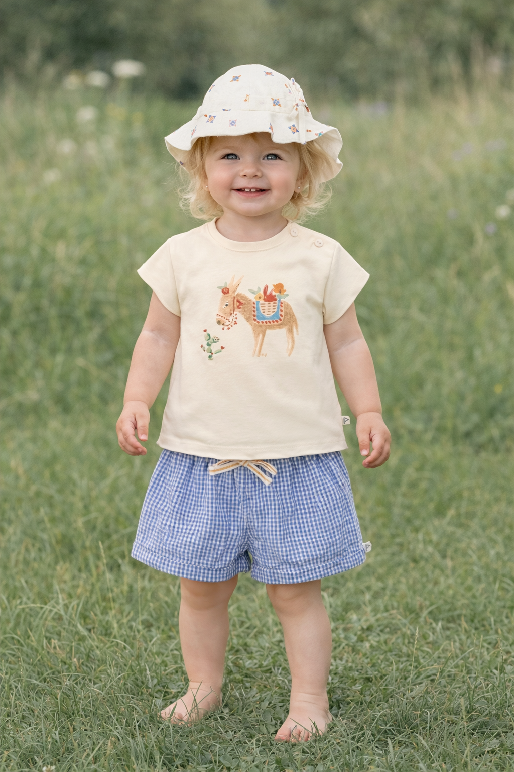 Meisje draagt blauw-wit geruite short en tshirt ecru met ezelprint