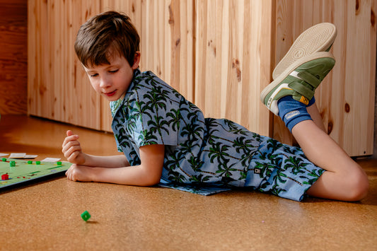 Jongen draagt blauwe short met palmbomen en hemd met palmbomen