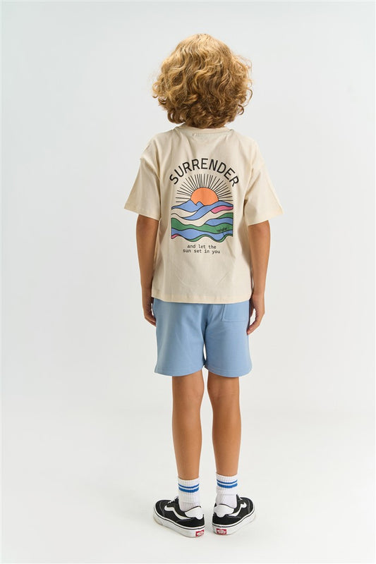 jongen draagt tshirt tuck van the new met zonsondergang print op de rugzijde