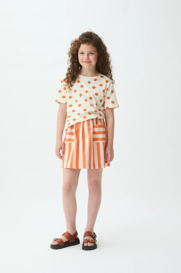 Meisje draagt oranje t-shirt met all-over print van Compañia Fantástica