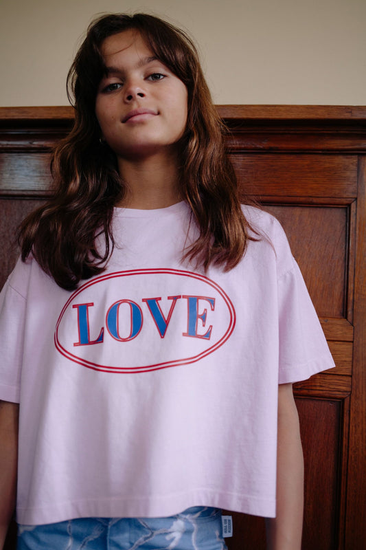 Meisje draagt lichtroze crop top met Love print
