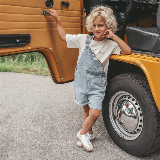 jongen draagt salopette light blue denim voorzijde