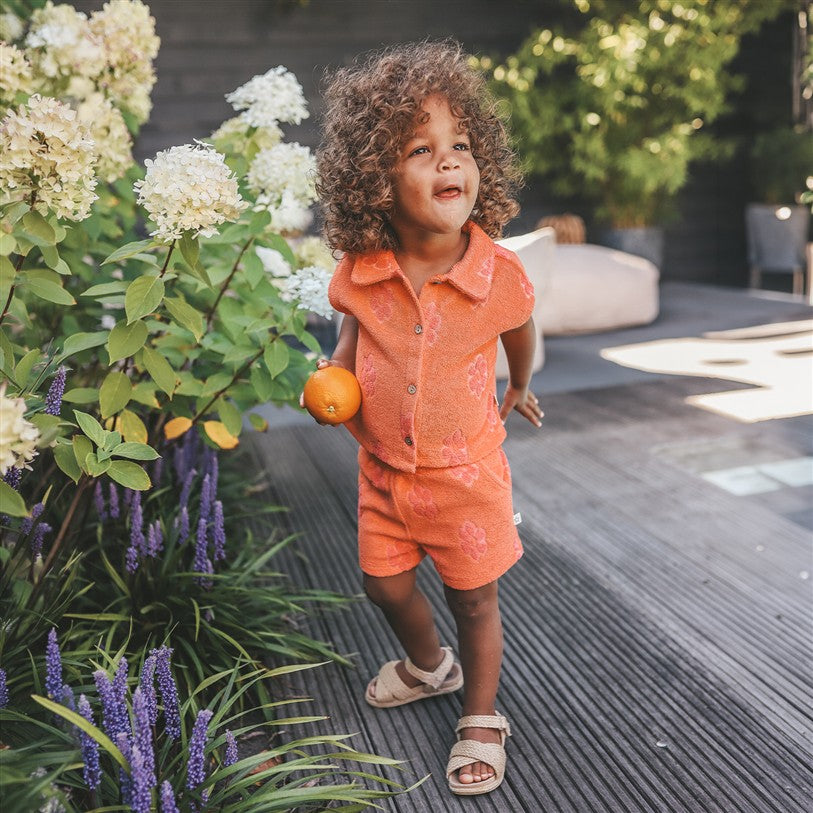 meisje draagt koraalroze hemd en short met bloemen van your wishes