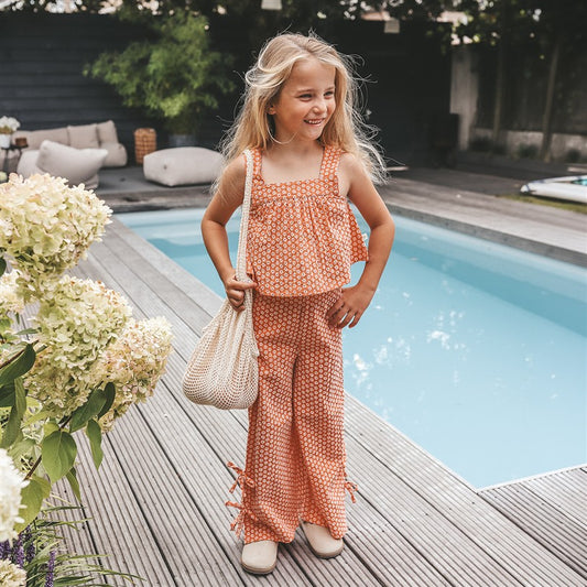 meisje draagt koraalroze top en broek in broderie van your wishes