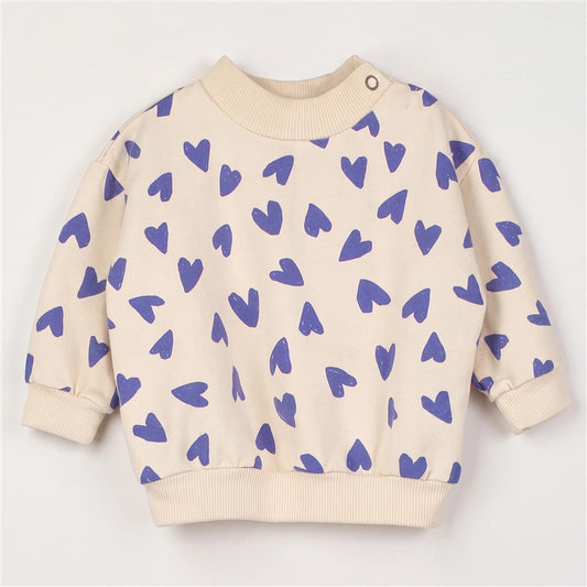 Crèmekleurige baby sweater met all-over blauwe hartjes.