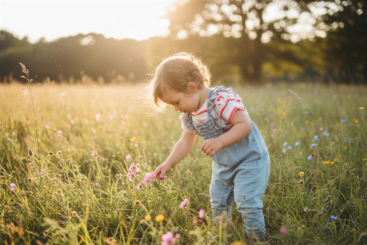 Peuter in denim flower salopette en gestreept blush t-shirt in een bloemenweide