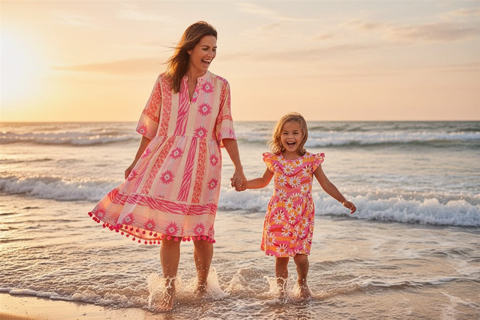 Dame draagt neon roze damesjurk Lotte van Danamade samen met meisje die roze jurk demmy met bloemenprint draagt
