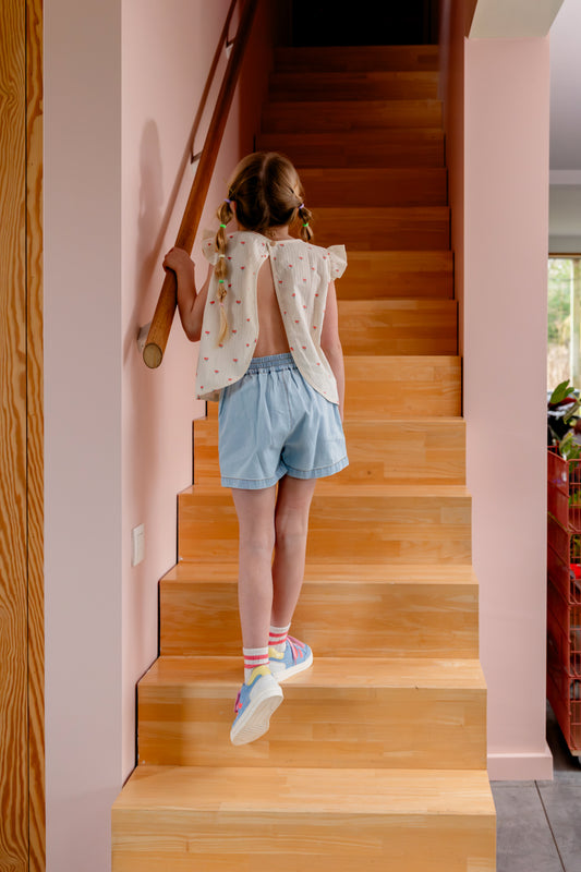 Kind draagt lichtblauwe chambray short achterkant