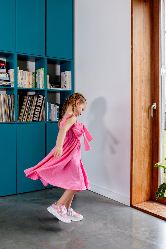 Meisje draagt roze jurk met strik detail
