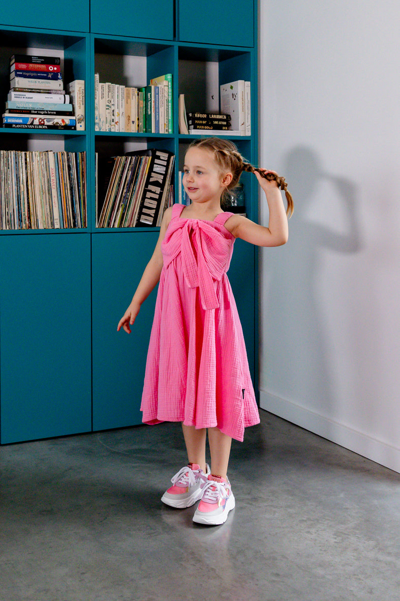Detail grote strik vooraan op roze kinderjurk