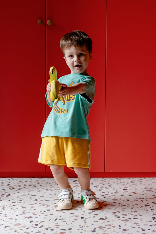 Kind draagt gele badstof short
