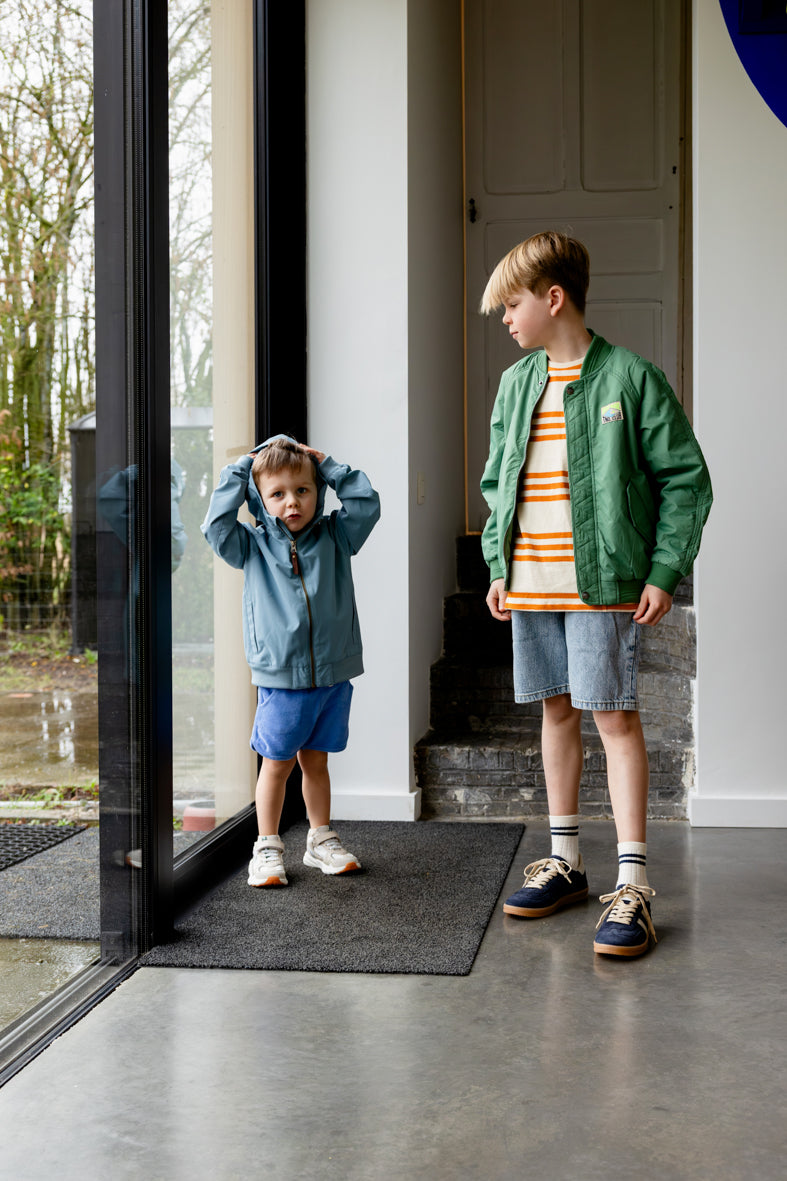 Jongen draagt blauwe badstof short van Daily Brat rechtopstaand.
