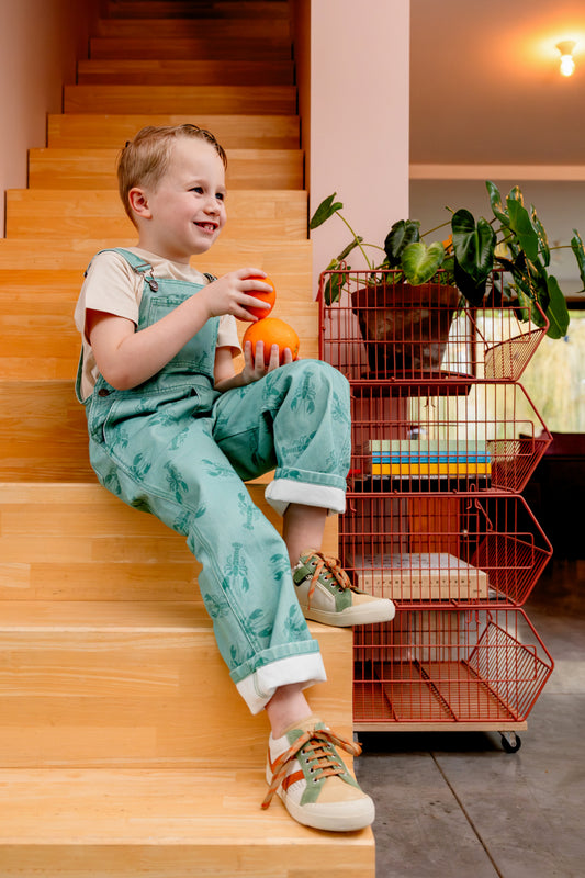 Jongen draagt groene salopette met kreeften