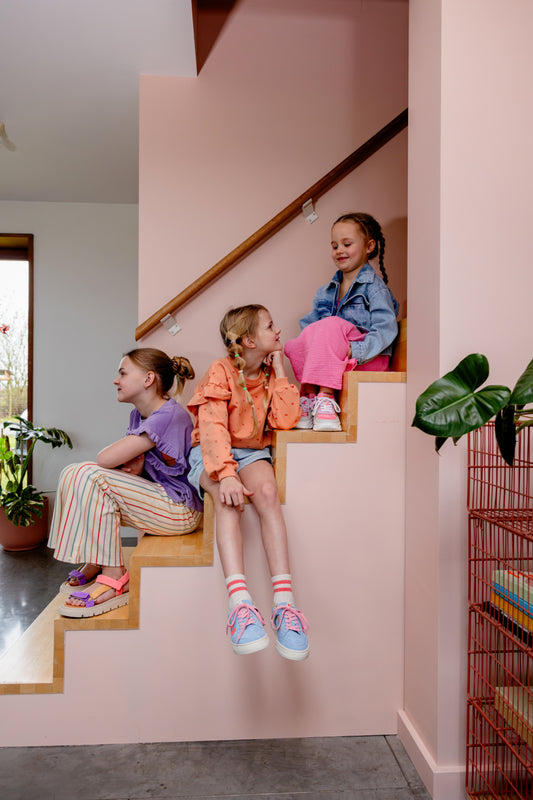 Kind draagt oranje-roze sweater met bloemetjes