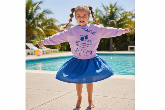 Meisje draagt lila sweater met Morning Hugs print en koningsblauwe tetra rok
