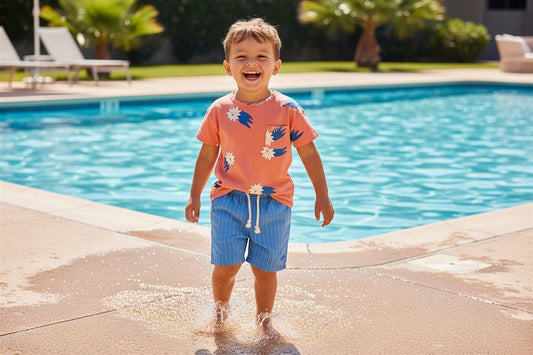 Jongen draagt oranje t-shirt met sterren
en blauwe gestreepte bermuda