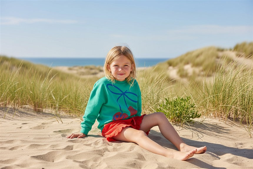 Meisje draagt groene sweater met kers