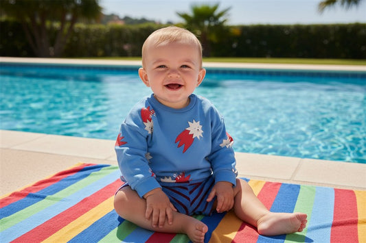 Baby draagt blauwe sweater met sterren met blauw gestreept badstof shortje