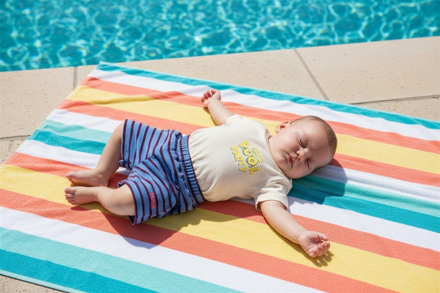 Baby draagt ecru t-shirt met Pool Party print en blauw gestreept badstof shortje
