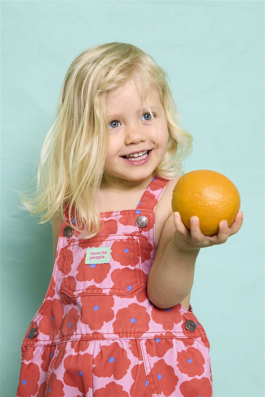 Baby draagt roze salopette met klaprozen
