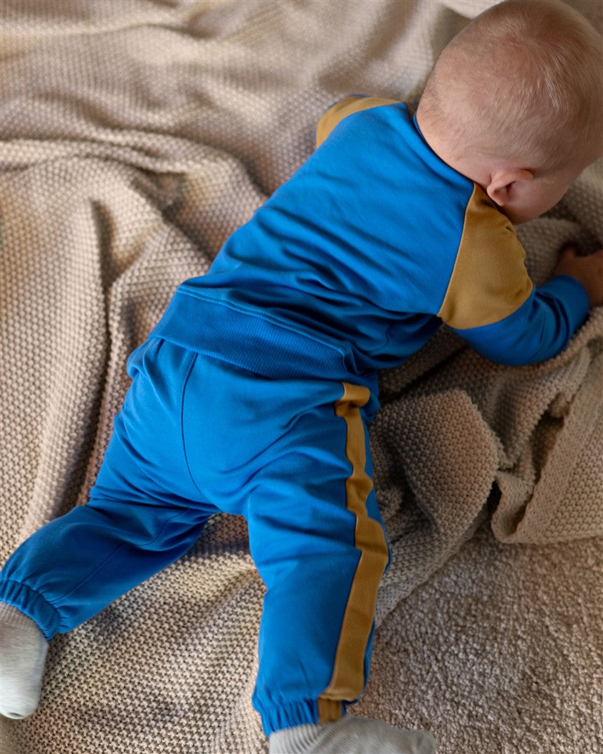 Blauwe baby jongens broek met gele strepen aan de zijkanten.