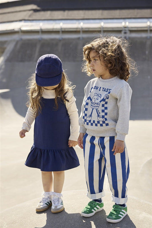 Kind draagt wit-blauwe gestreepte baggy pants